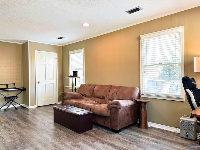 living room with wood finished floors, crown molding, and visible vents