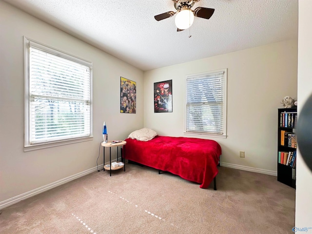 carpeted bedroom featuring baseboards, a textured ceiling, and a ceiling fan