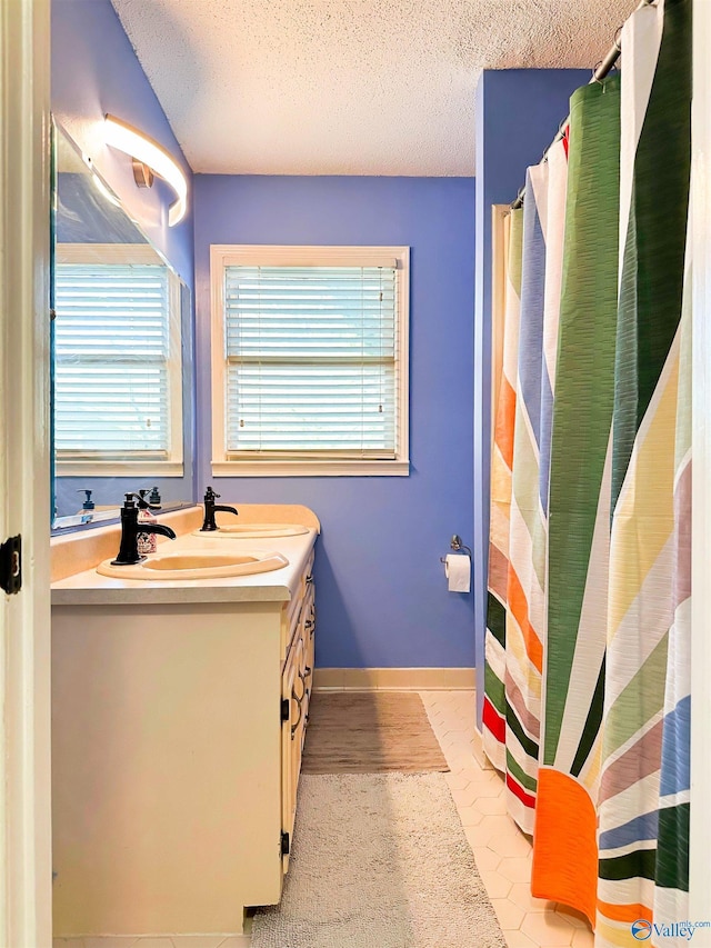 bathroom featuring a healthy amount of sunlight, baseboards, vanity, and a textured ceiling