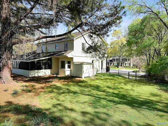 back of house featuring a lawn, stucco siding, a sunroom, and fence