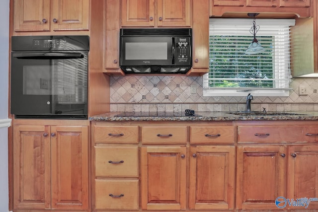 kitchen featuring sink, backsplash, black appliances, decorative light fixtures, and dark stone counters