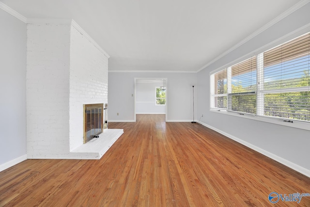 unfurnished living room featuring brick wall, ornamental molding, a brick fireplace, and hardwood / wood-style floors