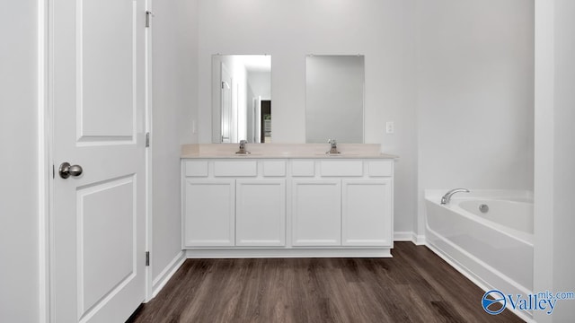 bathroom with a washtub, vanity, and wood-type flooring