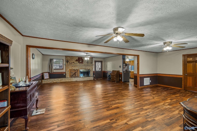 living room featuring wood walls, a textured ceiling, a brick fireplace, crown molding, and dark hardwood / wood-style floors