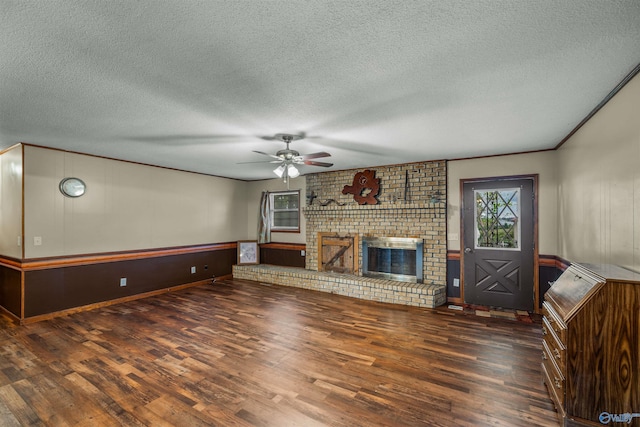 unfurnished living room with dark wood-type flooring, a brick fireplace, a textured ceiling, and ceiling fan