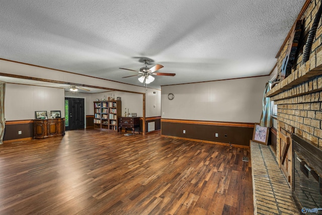 unfurnished living room with ornamental molding, dark hardwood / wood-style floors, a textured ceiling, and a fireplace