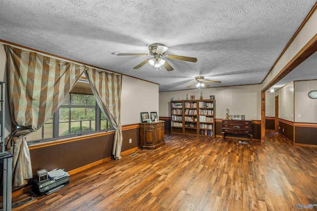 miscellaneous room featuring a textured ceiling, dark hardwood / wood-style flooring, ceiling fan, wooden walls, and ornamental molding