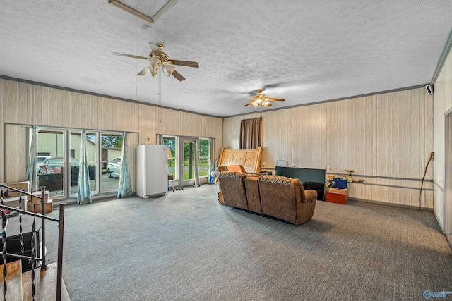 living room with wood walls, a textured ceiling, and ceiling fan