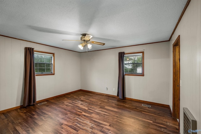 spare room with dark wood-type flooring, a healthy amount of sunlight, and a textured ceiling