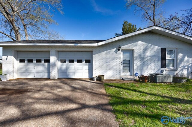 view of front facade featuring a garage, central AC unit, and a front yard