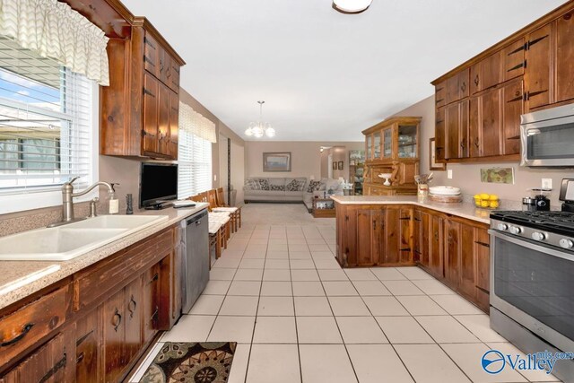 kitchen with stainless steel appliances, an inviting chandelier, sink, decorative light fixtures, and light tile patterned floors