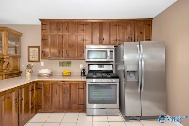 7228 Old Railroad Bed Rd, Toney, AL 35773 - kitchen featuring light countertops, light tile patterned flooring, brown cabinetry, and stainless steel appliances
