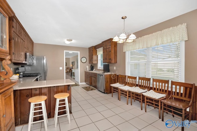 7228 Old Railroad Bed Rd, Toney, AL 35773 - kitchen featuring brown cabinets, stainless steel appliances, a peninsula, light countertops, and a chandelier