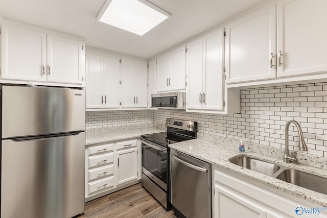2043 Woodlawn Dr SW Unit 2043, Huntsville, AL 35802 - kitchen featuring stainless steel appliances, white cabinets, light stone counters, and decorative backsplash