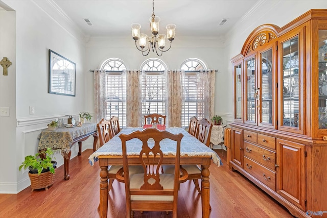 dining room featuring a wealth of natural light, a notable chandelier, light wood finished floors, and crown molding