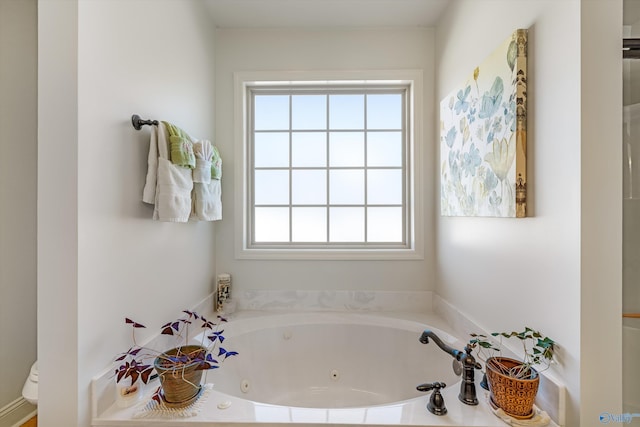 bathroom with a jetted tub and toilet