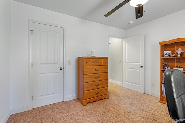 office space featuring light colored carpet, ceiling fan, and baseboards