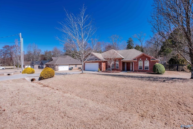 ranch-style home with driveway, brick siding, an attached garage, and fence