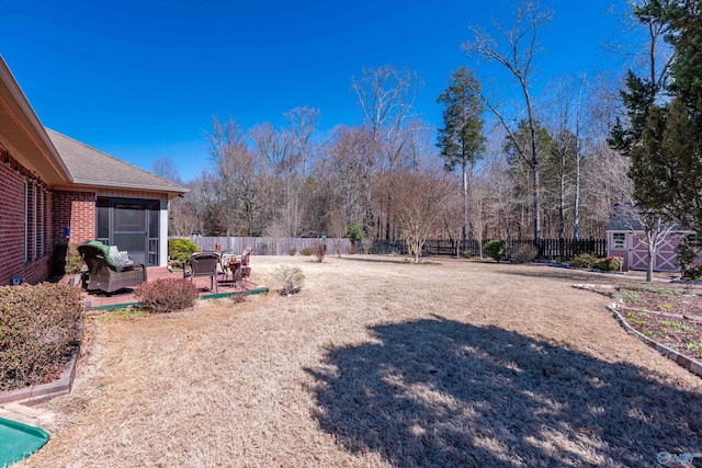 view of yard featuring a fenced backyard, a shed, a patio, and an outbuilding