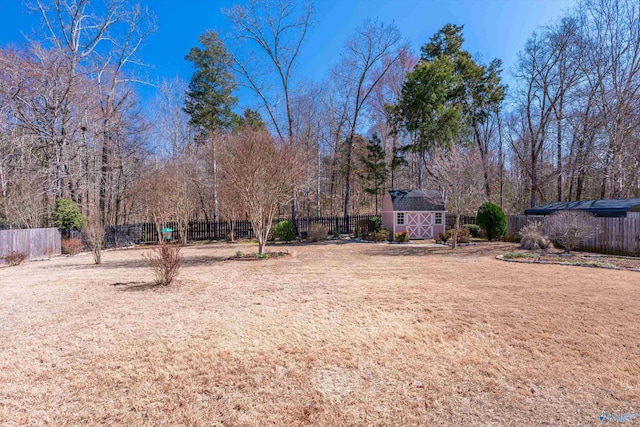 view of yard featuring a fenced backyard, a storage unit, and an outdoor structure