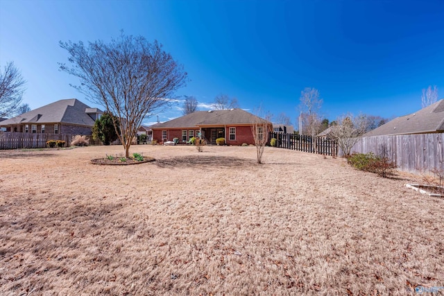 rear view of house featuring fence and brick siding