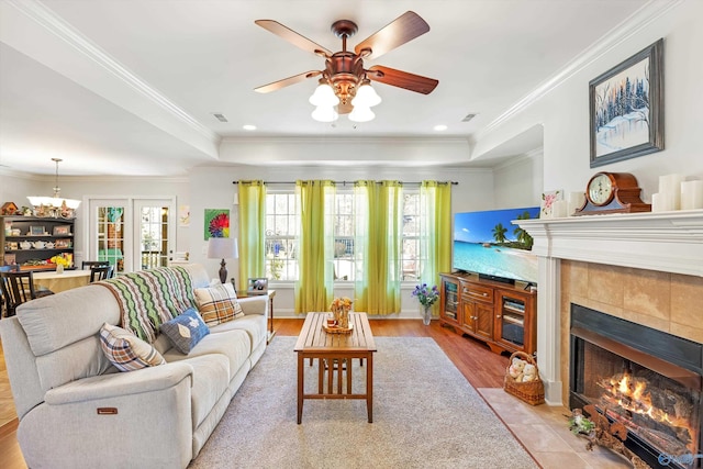 living area with ornamental molding, a tray ceiling, a fireplace, and visible vents