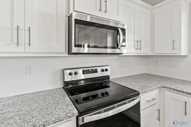 kitchen with white cabinetry, appliances with stainless steel finishes, backsplash, and light stone counters