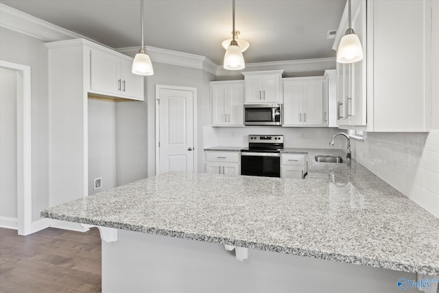 kitchen with appliances with stainless steel finishes, pendant lighting, sink, white cabinets, and kitchen peninsula