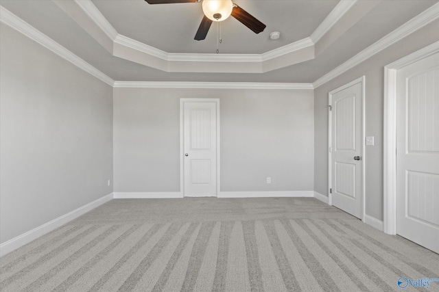 carpeted empty room featuring ceiling fan, ornamental molding, and a raised ceiling