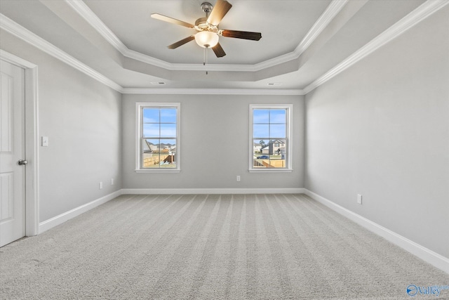 carpeted spare room with crown molding, ceiling fan, a raised ceiling, and a wealth of natural light