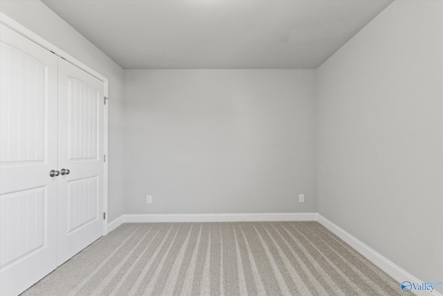 unfurnished bedroom featuring light carpet and a closet