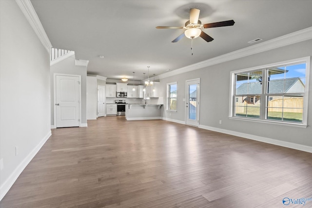 unfurnished living room featuring hardwood / wood-style floors, ornamental molding, and ceiling fan with notable chandelier