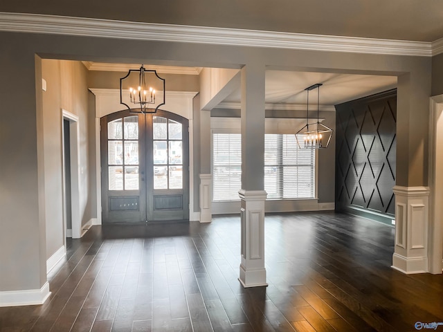 entrance foyer with an inviting chandelier, crown molding, french doors, dark hardwood / wood-style flooring, and ornate columns