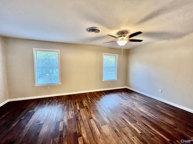 spare room featuring a ceiling fan, dark wood-type flooring, baseboards, and visible vents
