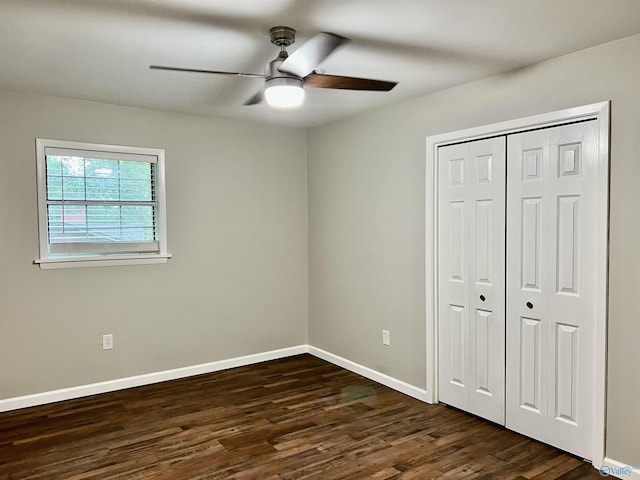 unfurnished bedroom with baseboards, dark wood-style floors, a closet, and ceiling fan
