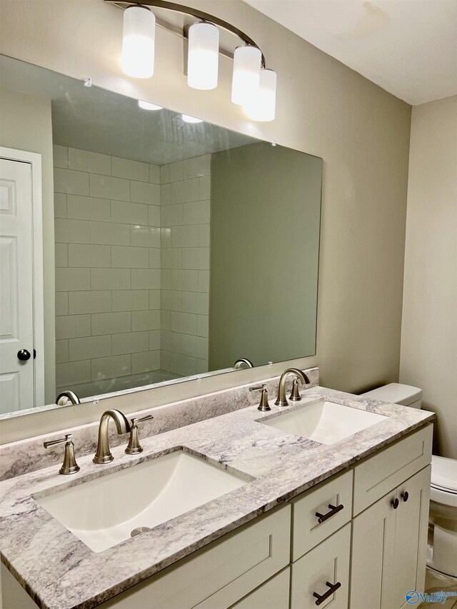 bathroom featuring toilet, a sink, and double vanity