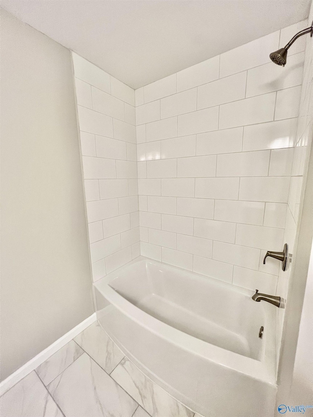 bathroom with marble finish floor,  shower combination, and baseboards