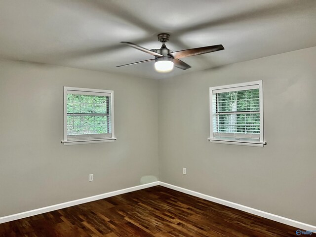 spare room featuring plenty of natural light, baseboards, dark wood-style flooring, and a ceiling fan
