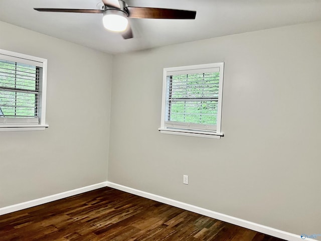 spare room featuring baseboards, a healthy amount of sunlight, ceiling fan, and dark wood finished floors