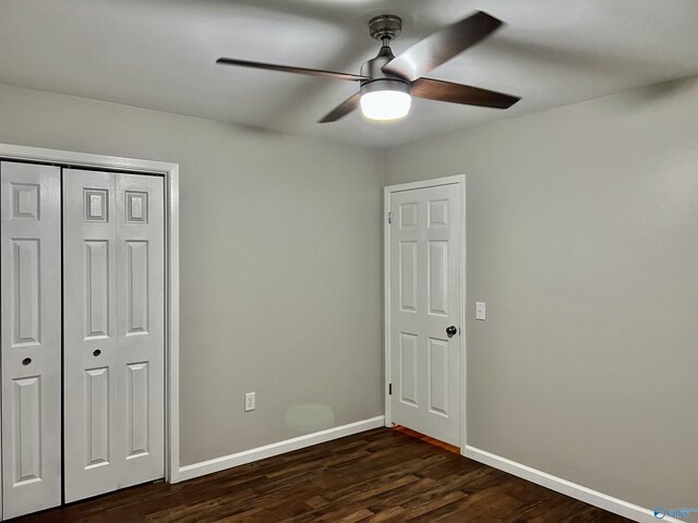 unfurnished bedroom with a closet, baseboards, ceiling fan, and dark wood finished floors