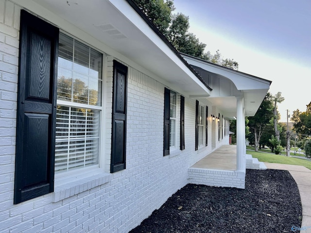 view of property exterior featuring covered porch and brick siding