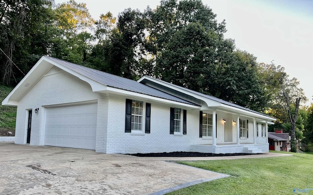 single story home featuring a front yard, concrete driveway, an attached garage, brick siding, and metal roof