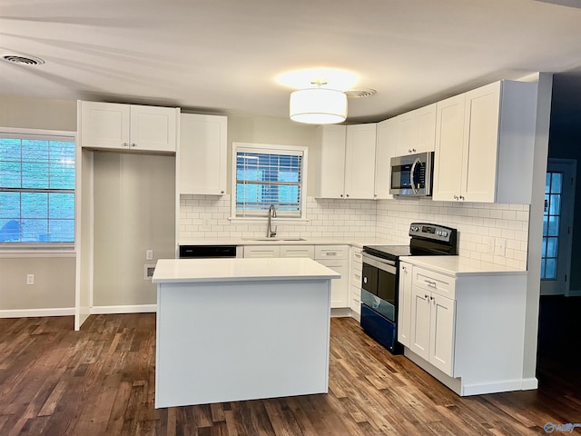 kitchen featuring dark wood-style flooring, visible vents, appliances with stainless steel finishes, a sink, and a center island