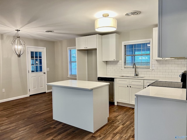 kitchen featuring a sink, a kitchen island, stainless steel dishwasher, visible vents, and dark wood-style flooring