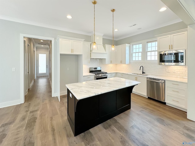 kitchen featuring sink, hanging light fixtures, appliances with stainless steel finishes, a kitchen island, and white cabinets