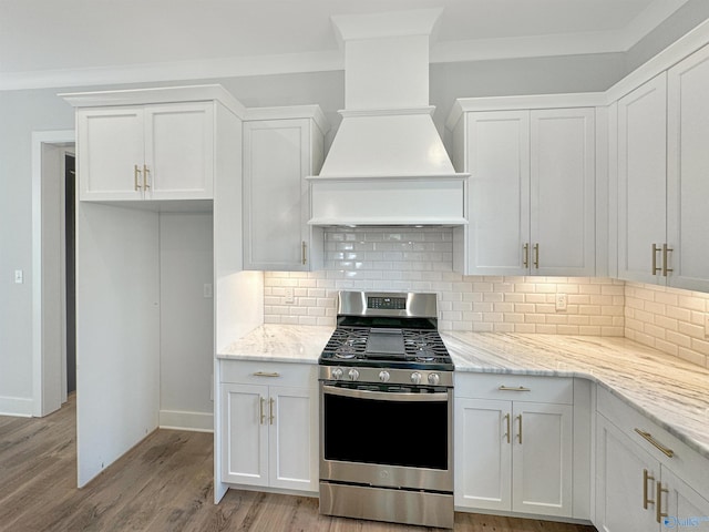 kitchen with light stone counters, gas stove, custom range hood, and white cabinets