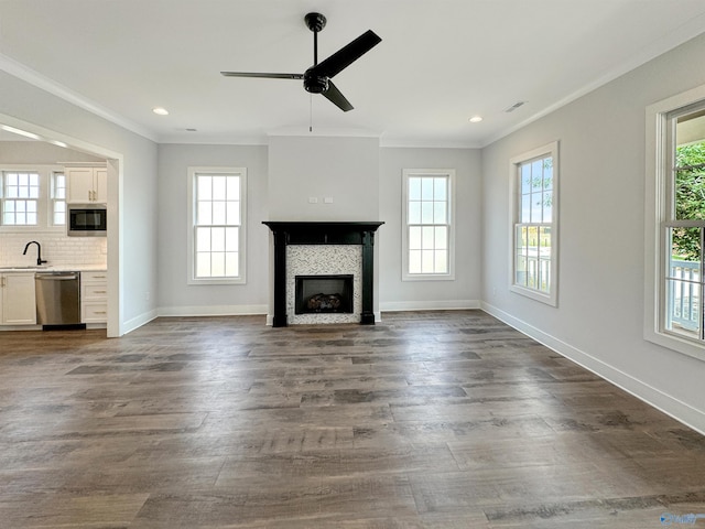 unfurnished living room with dark hardwood / wood-style flooring, sink, crown molding, and a tile fireplace