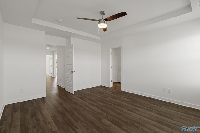 unfurnished room featuring ceiling fan, a tray ceiling, and dark hardwood / wood-style floors