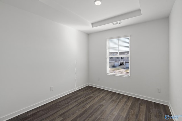 spare room with dark hardwood / wood-style flooring and a raised ceiling