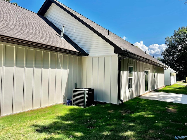 view of side of property featuring central AC unit and a yard